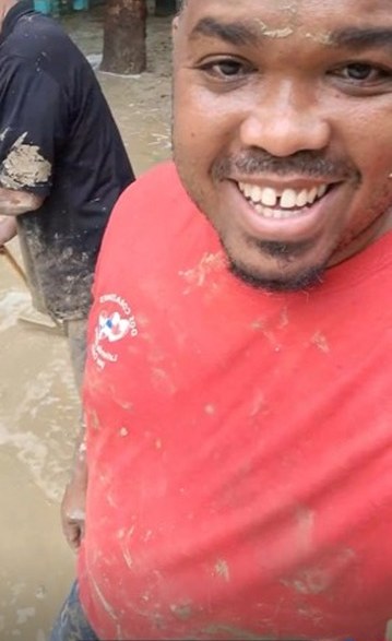 Benjamin Núñez smiling, covered in mud, outside the Makarios school in Montellano after a day of cleanup.