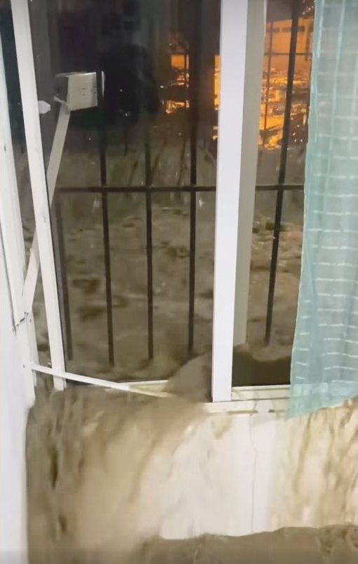 Flood water rushing past a door during the April 12 flood in Montellano.