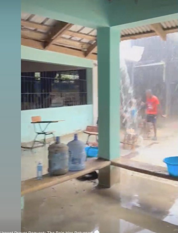 Rain pouring onto the Makarios school grounds, water jugs stored for drinking because the aqueducts failed again.