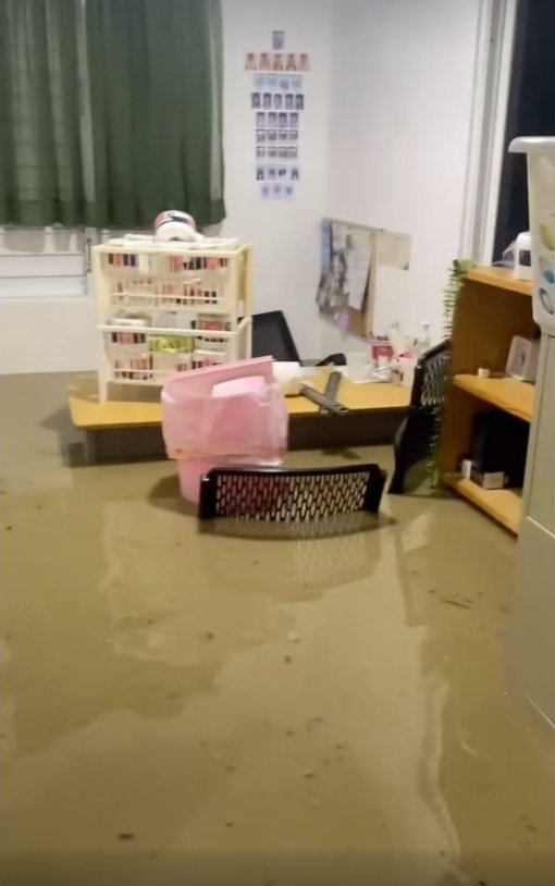 A flooded office at the Makarios campus, with debris floating in brown water.